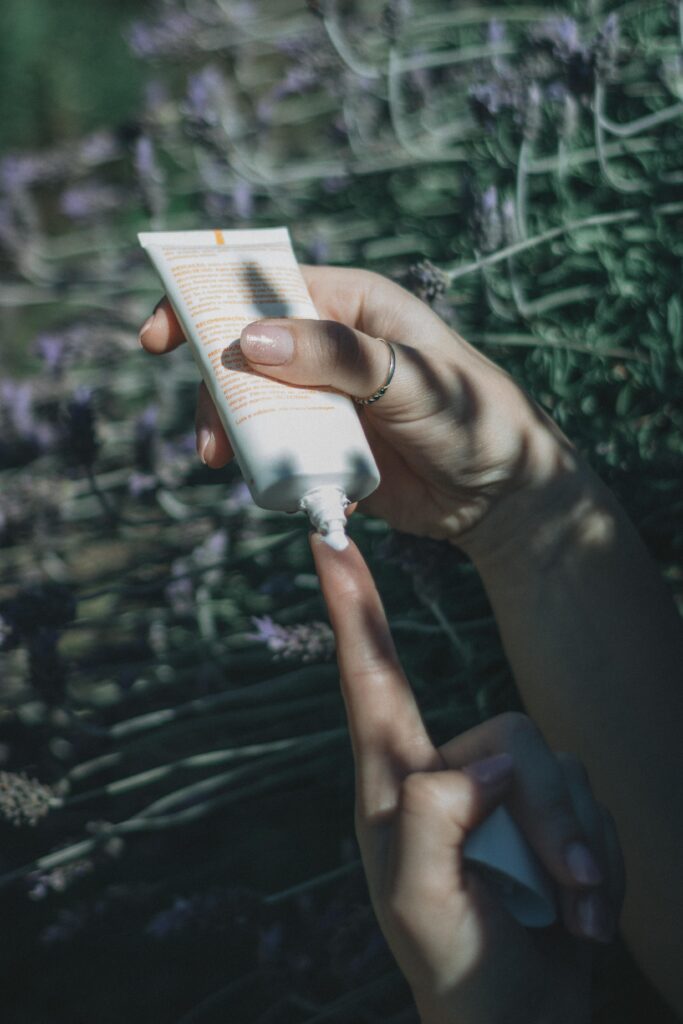 pexels-photo-34103036-34103036 Close-up of hands with skincare cream against a lavender backdrop.