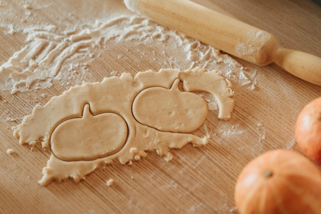 pexels-photo-5471933-5471933 Pumpkin-shaped cookie dough on a wooden surface, perfect for Halloween baking.