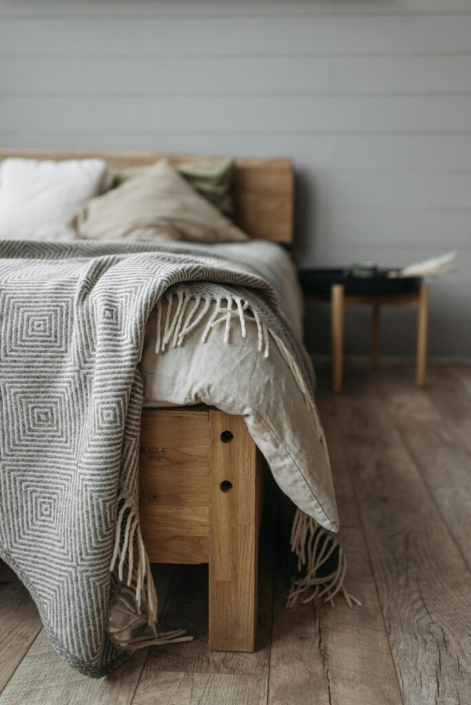 pexels-photo-7055750-7055750 A cozy fall bedroom with a wooden bed, pillows, and a patterned blanket on a wooden floor.