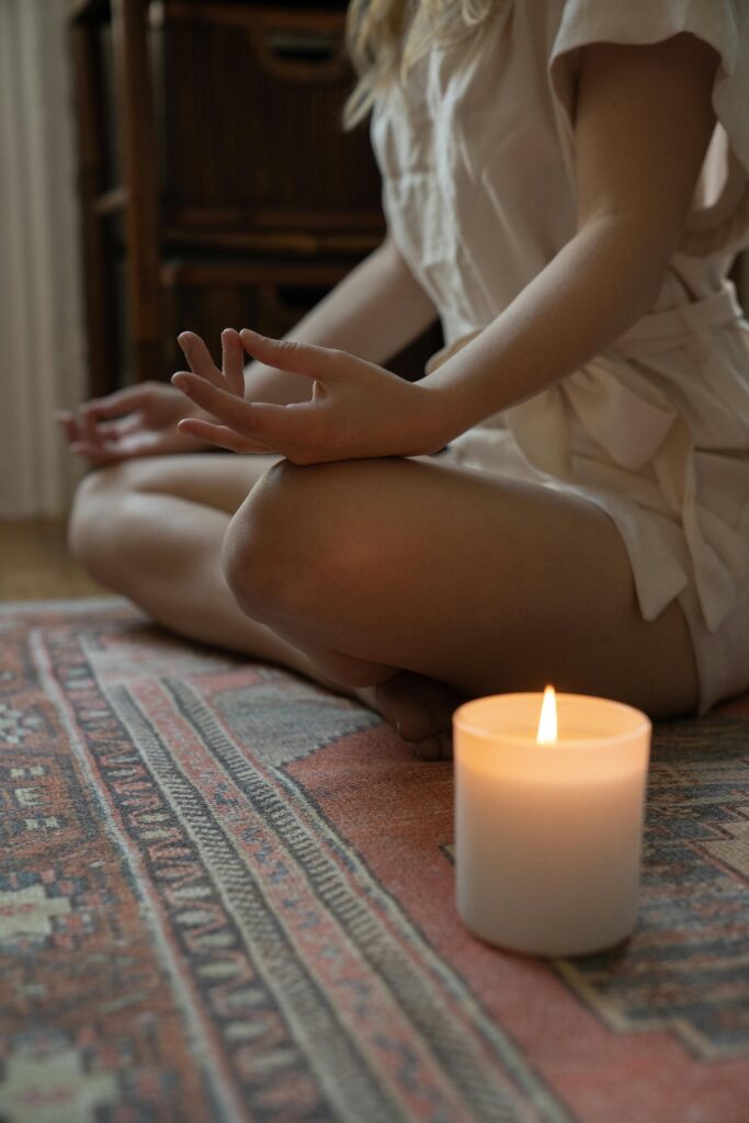 Experience tranquility with a lit candle and meditative pose, ideal for mindfulness practices.