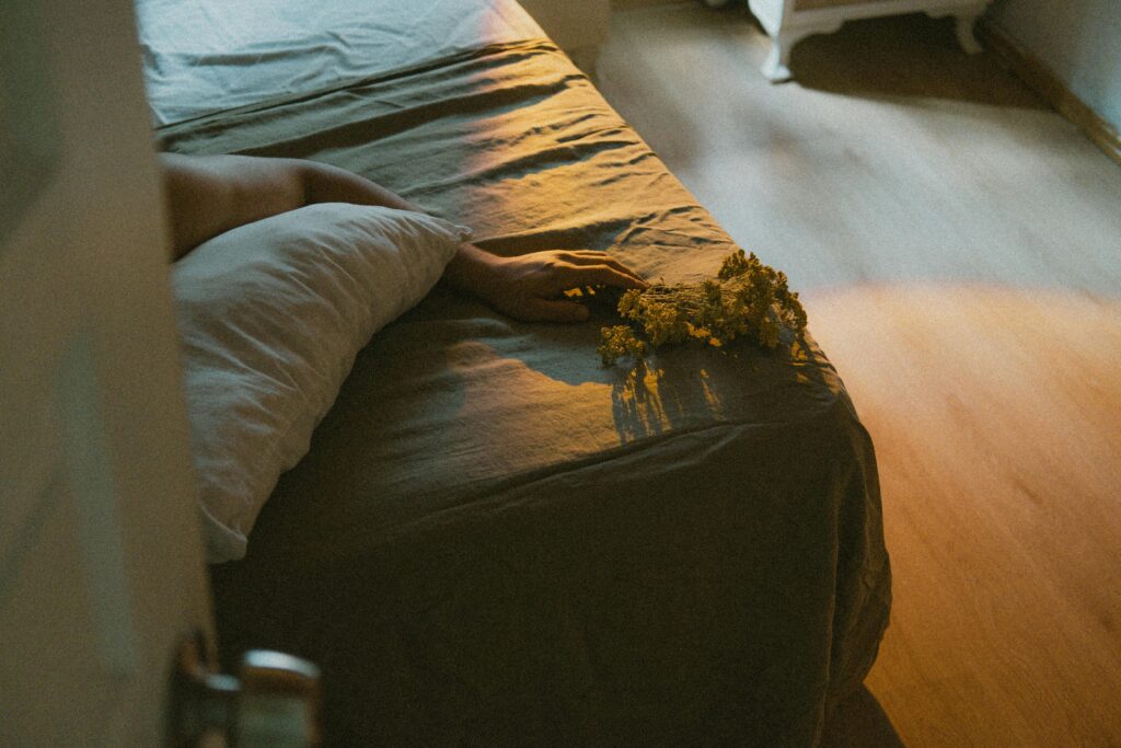 pexels-photo-18233939-18233939 A peaceful morning scene with a hand resting on a bed holding a bouquet. Warm light adds a serene touch.