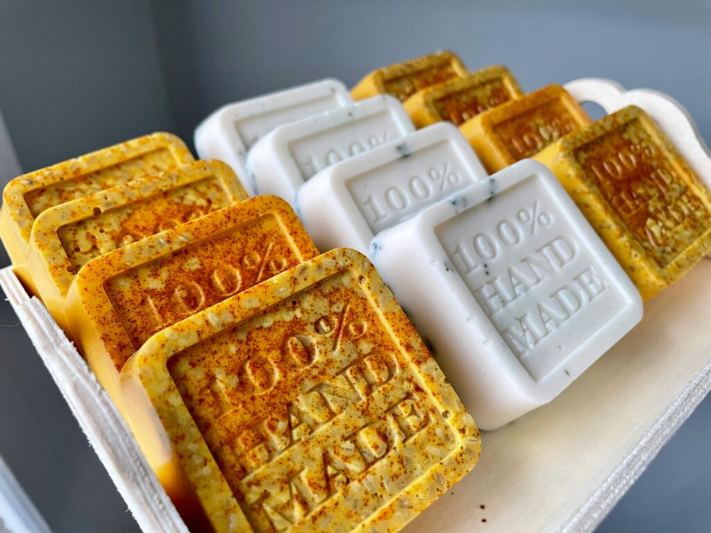 pexels-photo-31517862-31517862 Handmade artisan soaps with '100% Hand Made' text, showcasing organic ingredients and craftsmanship.