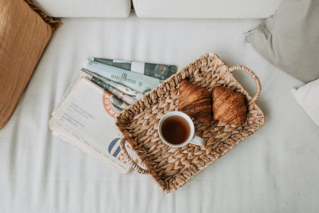 pexels-photo-5357348-5357348 A cozy morning scene with coffee, croissants, and a woven tray on a white sofa.